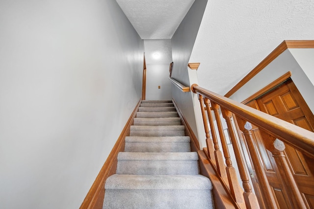 staircase featuring a textured ceiling