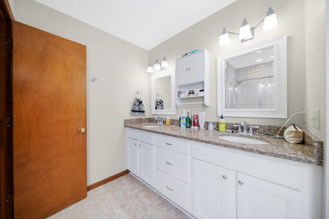 bathroom with baseboards, a sink, a tile shower, and double vanity