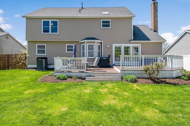 rear view of house featuring a lawn, fence, a chimney, and cooling unit