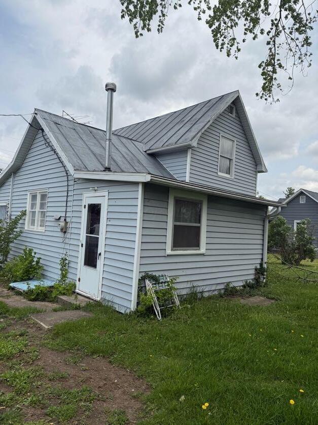 back of property with a standing seam roof, a lawn, and metal roof