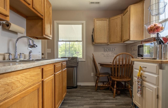 kitchen with visible vents, baseboards, light countertops, a sink, and dark wood finished floors