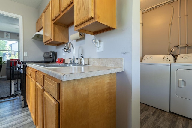 kitchen featuring wood finished floors, a sink, washing machine and dryer, and gas stove