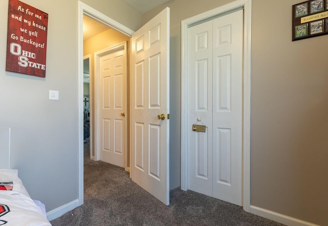 hall featuring baseboards and dark carpet