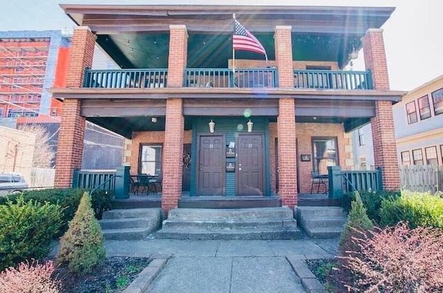 property entrance with a porch, brick siding, and a balcony