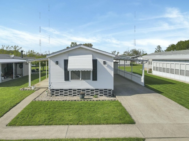 manufactured / mobile home with concrete driveway, a carport, and a front lawn