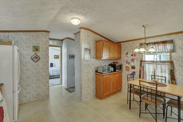 kitchen featuring stainless steel microwave, brown cabinetry, freestanding refrigerator, crown molding, and wallpapered walls