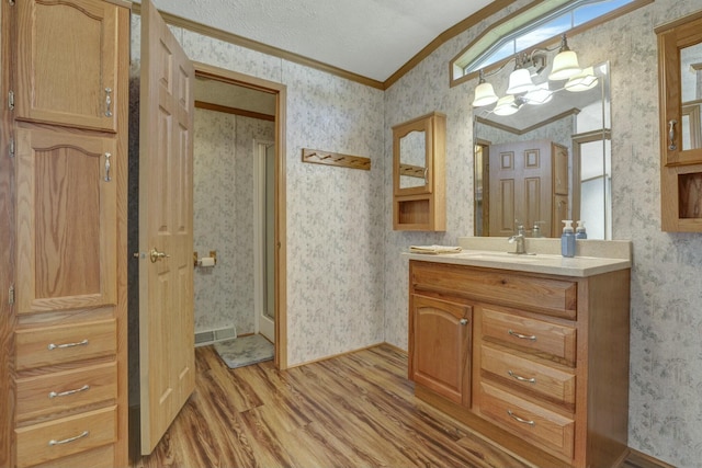 bathroom with wallpapered walls, a chandelier, wood finished floors, and ornamental molding