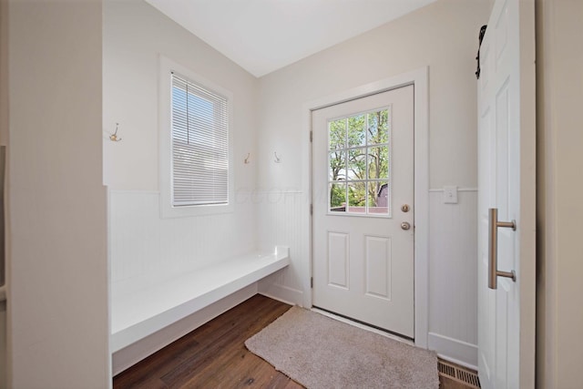entryway with dark wood-style flooring, visible vents, and a wainscoted wall