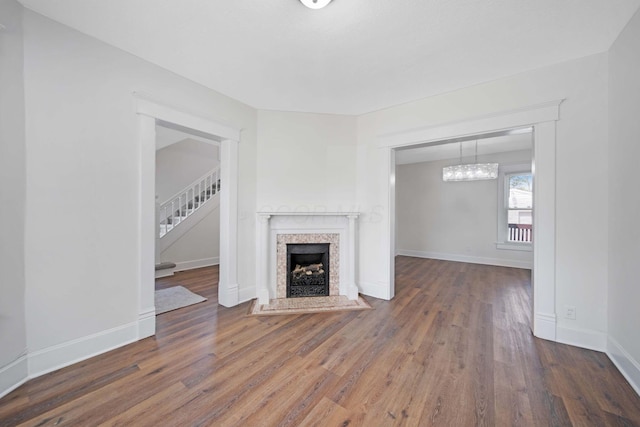 unfurnished living room featuring stairs, baseboards, wood finished floors, and a tile fireplace