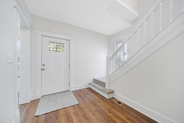 foyer entrance featuring visible vents, baseboards, wood finished floors, and stairway