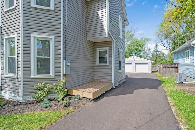 view of side of property with a detached garage, an outdoor structure, and central AC