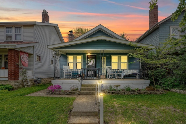 view of front facade featuring a porch, a front lawn, and a chimney