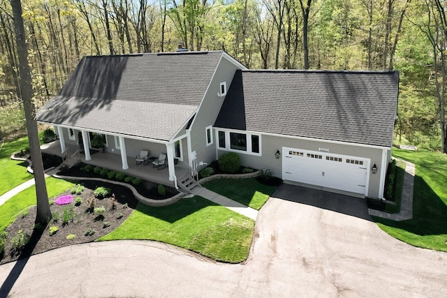 view of front of home featuring roof with shingles, covered porch, a front lawn, and aphalt driveway