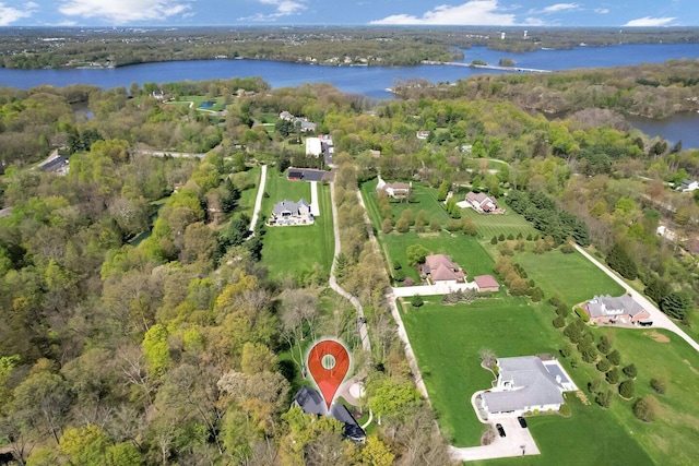 birds eye view of property featuring a water view and a wooded view