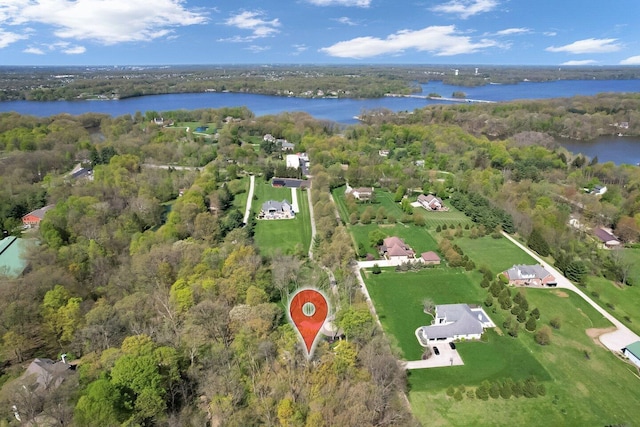 birds eye view of property featuring a water view and a wooded view