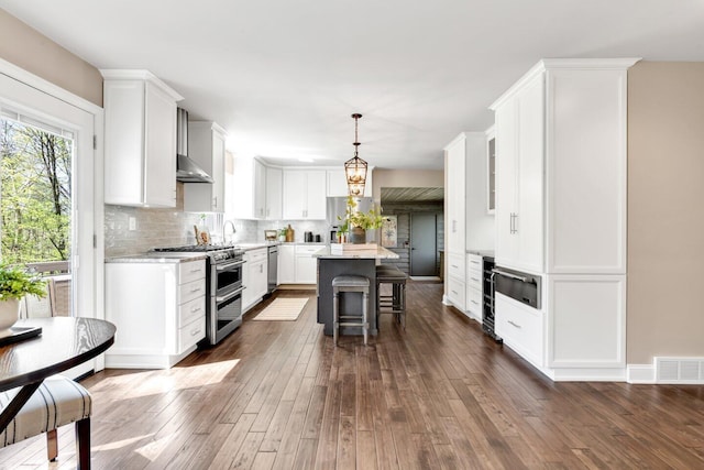 kitchen featuring decorative backsplash, dark wood-style floors, a center island, white cabinetry, and appliances with stainless steel finishes