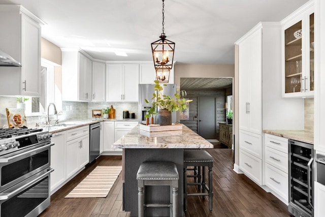 kitchen featuring decorative backsplash, a kitchen island, beverage cooler, a sink, and appliances with stainless steel finishes