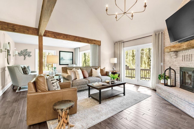 living room featuring high vaulted ceiling, a brick fireplace, dark wood-style floors, and a notable chandelier