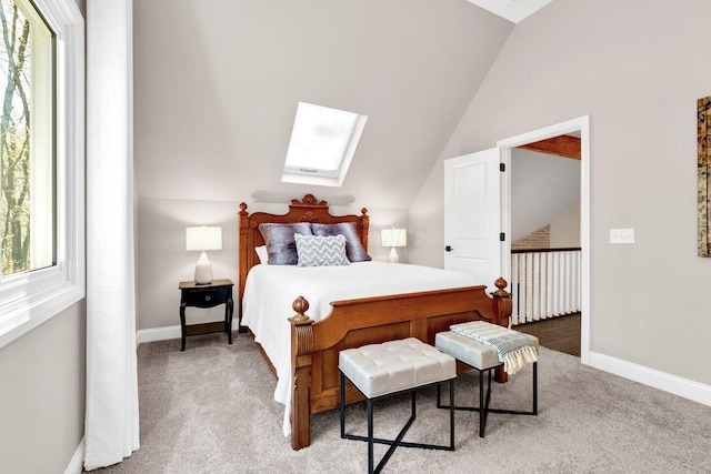 bedroom with baseboards, carpet flooring, vaulted ceiling with skylight, and multiple windows