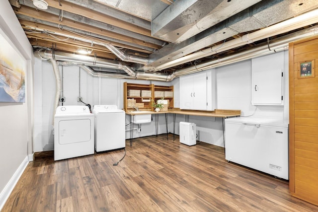washroom with cabinet space, washer and dryer, a sink, dark wood finished floors, and baseboards