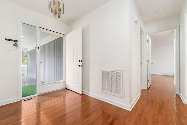 foyer with visible vents, wood-type flooring, baseboards, and a chandelier