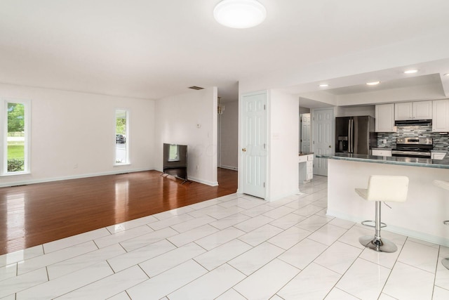 unfurnished living room featuring baseboards, recessed lighting, and light wood-style flooring