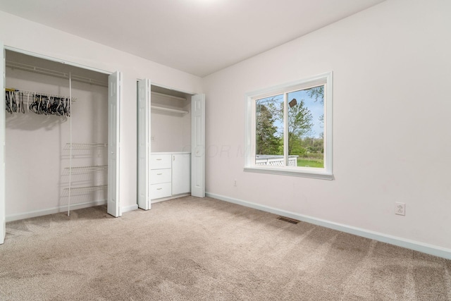 unfurnished bedroom with carpet floors, baseboards, multiple closets, and visible vents
