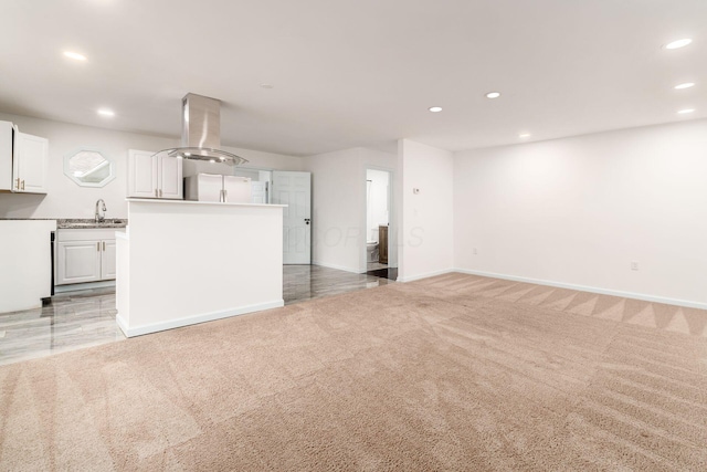 unfurnished living room featuring recessed lighting, a sink, baseboards, and light carpet