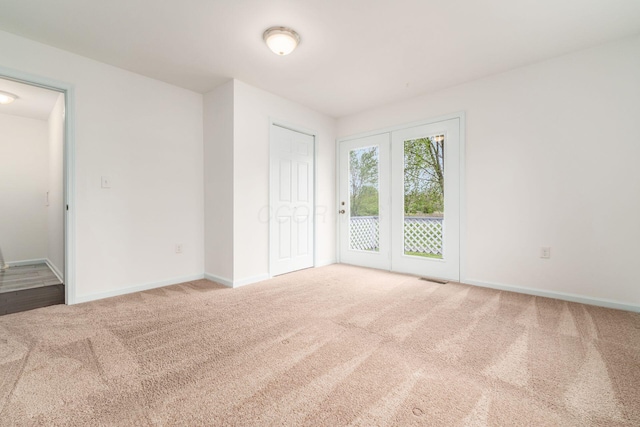 unfurnished bedroom with baseboards, access to outside, carpet flooring, and visible vents