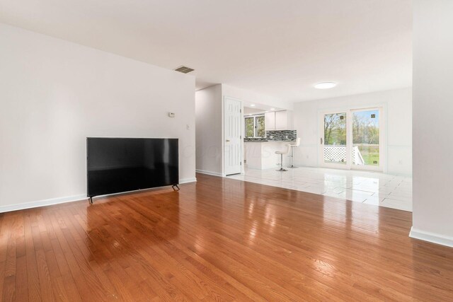 unfurnished living room featuring baseboards, visible vents, and hardwood / wood-style floors
