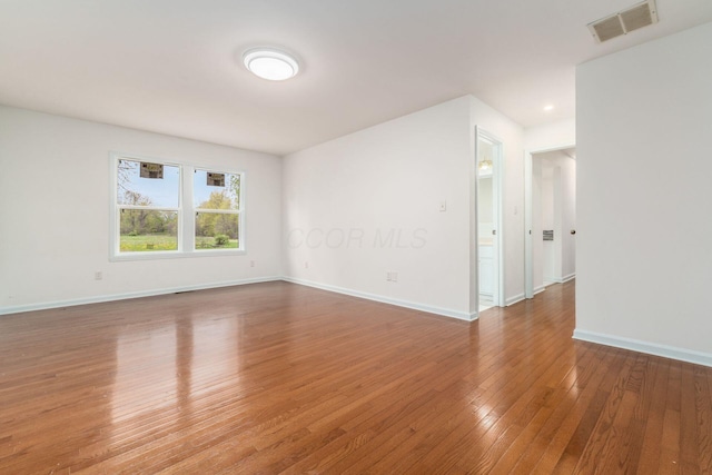 spare room featuring baseboards, hardwood / wood-style flooring, and visible vents