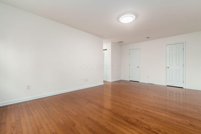 spare room with baseboards and wood finished floors