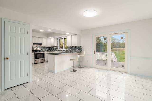 kitchen with electric range, a kitchen breakfast bar, a peninsula, backsplash, and under cabinet range hood