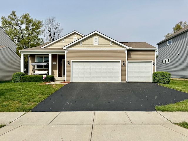 view of front of house with an attached garage, a front lawn, aphalt driveway, and covered porch