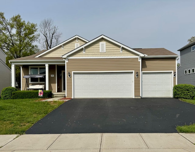 view of front facade featuring covered porch, an attached garage, driveway, and a front lawn