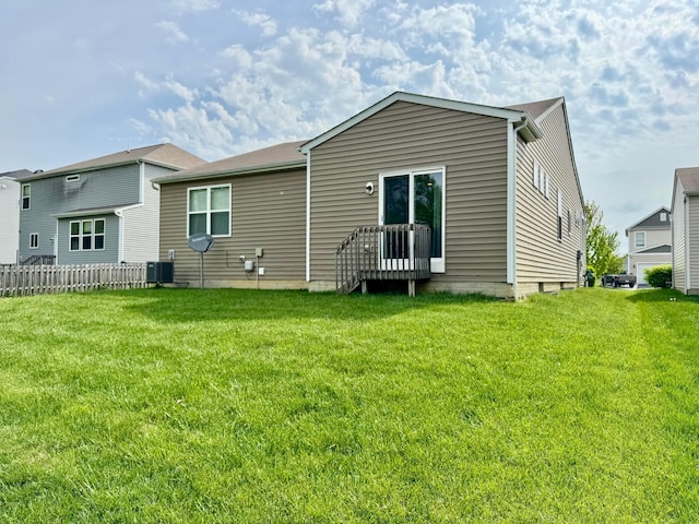 back of property with central air condition unit, fence, and a lawn