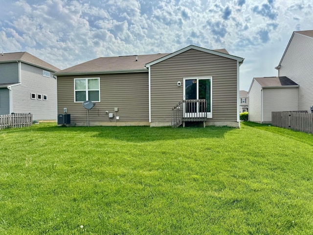 back of house featuring central air condition unit, fence, and a yard