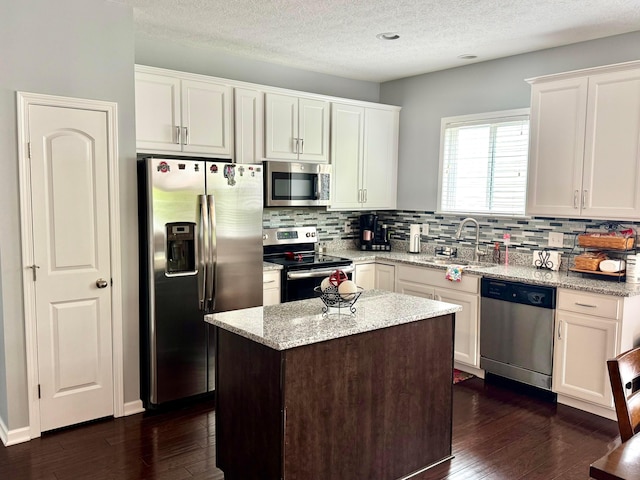 kitchen featuring a sink, appliances with stainless steel finishes, backsplash, and dark wood-style flooring