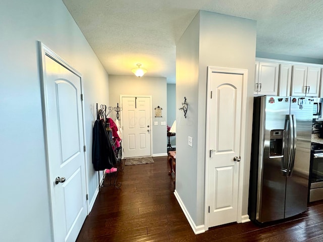 hallway featuring baseboards, dark wood-style floors, and a textured ceiling