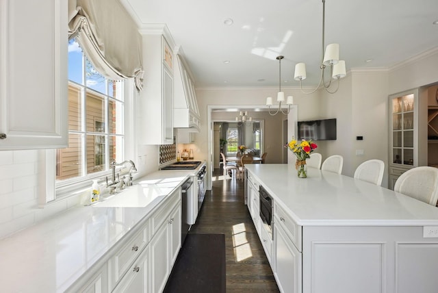 kitchen featuring white cabinets, an inviting chandelier, a sink, tasteful backsplash, and a spacious island