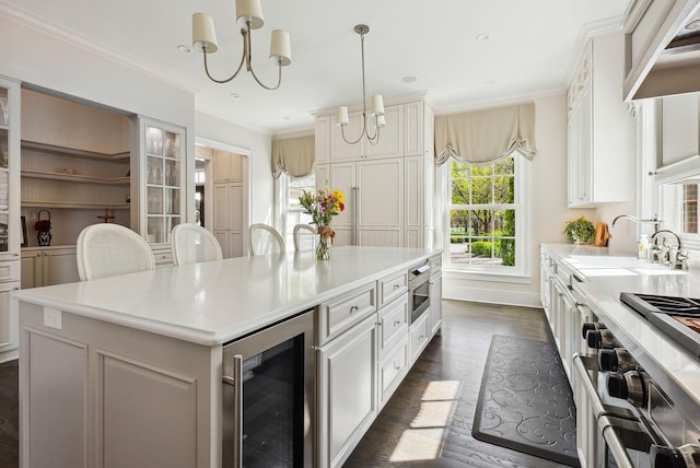 kitchen featuring a kitchen island, appliances with stainless steel finishes, light countertops, a notable chandelier, and wine cooler