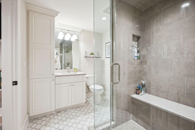bathroom with vanity, toilet, baseboards, and a stall shower