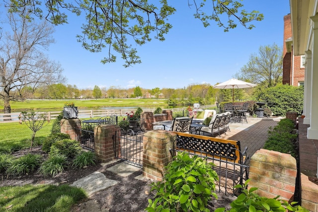 view of patio featuring outdoor dining area, a gate, fence, and a water view