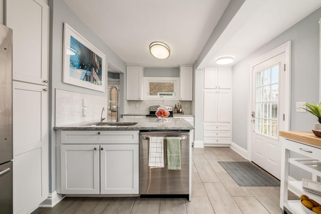 1938 W 5th Ave, Columbus, OH 43212 - kitchen featuring stainless steel appliances, a sink, white cabinetry, light stone countertops, and tasteful backsplash