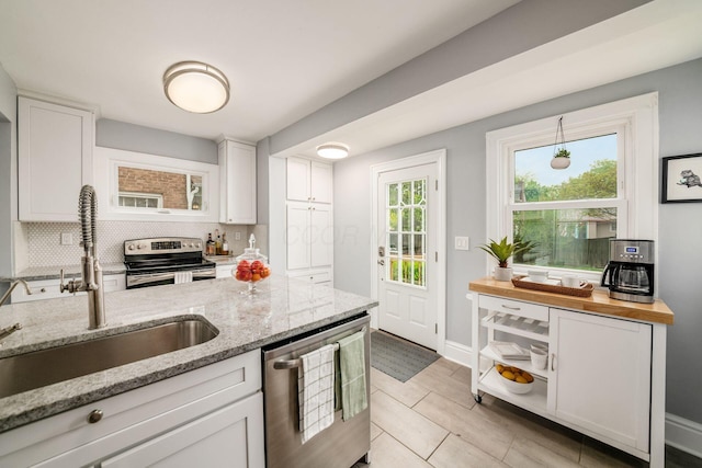 1938 W 5th Ave, Columbus, OH 43212 - kitchen featuring stainless steel appliances, a sink, decorative backsplash, and white cabinetry