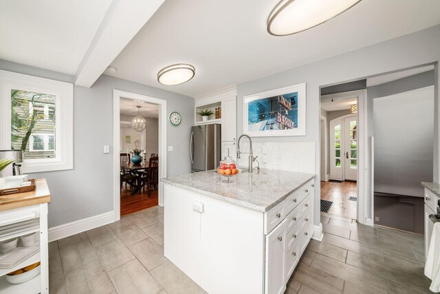 1938 W 5th Ave, Columbus, OH 43212 - kitchen with freestanding refrigerator, white cabinets, backsplash, light stone countertops, and a sink