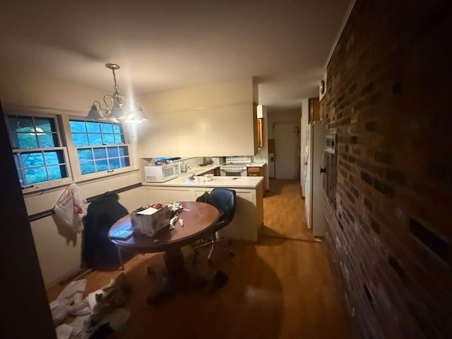 dining space with light wood-style floors, brick wall, and a chandelier