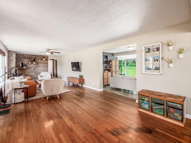 living area with ceiling fan, visible vents, baseboards, and hardwood / wood-style floors