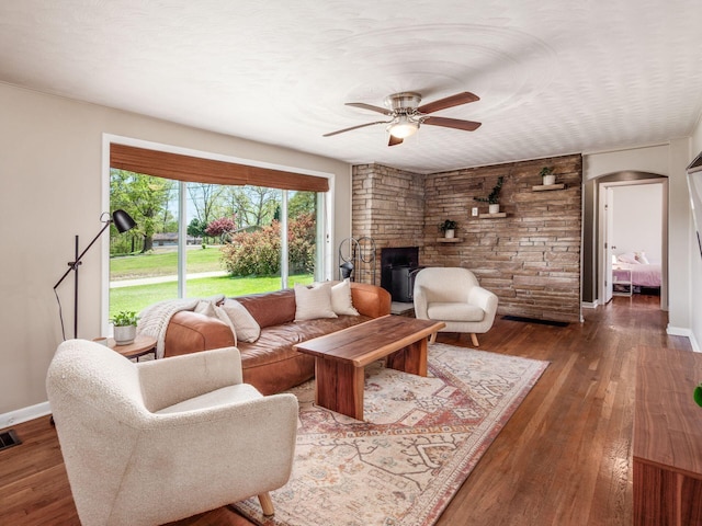 living room featuring arched walkways, baseboards, a ceiling fan, and hardwood / wood-style floors