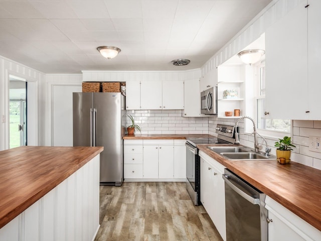 kitchen with a sink, wood counters, white cabinetry, and stainless steel appliances